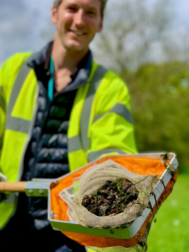 A Bristol Water worker holding a net toward the camera, filled with Zebra Mussels