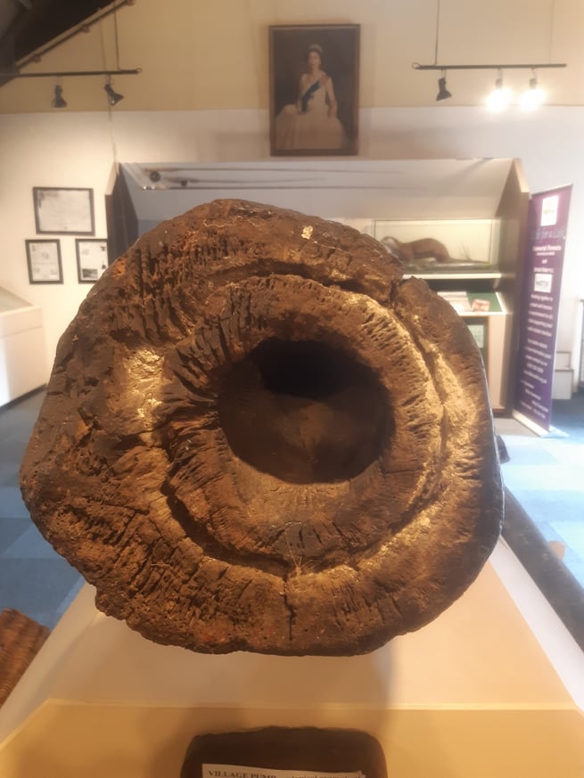 A close up picture of a wooden water pipe in a museum 