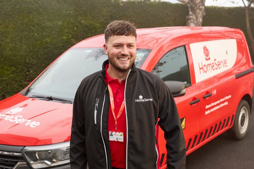 HomeServe plumber stood smiling next to sign written HomeServe van