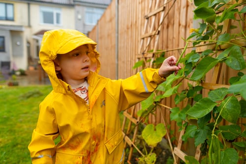 Child in a raincoat playing in a garden