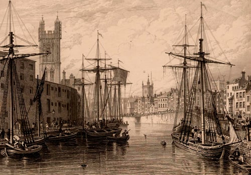 Black and white artwork depicting Bristol Harbourside in the 1700s, busy with boats and ship workers, with St Mary Redcliffe church in the background.  