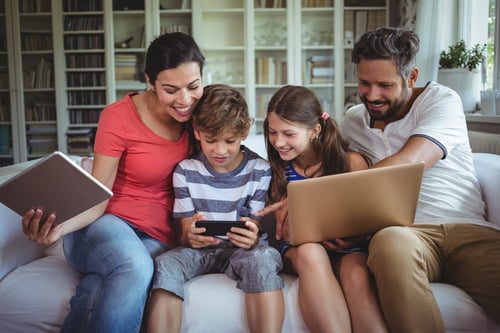 Happy family sitting on sofa and using laptop, mobile phone and digital tablet at home-1