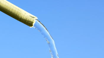yellow hosepipe pouring water in front of blue sky