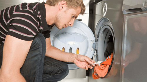 man is polo shirt loading the washing machine