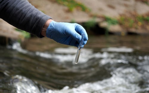 Water quality testing being carried out at a river using a test tube
