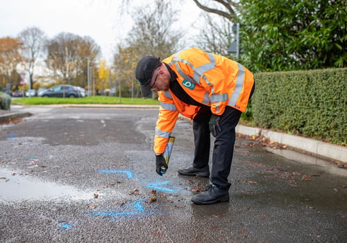 Man in high vis spraying blue lines on the road