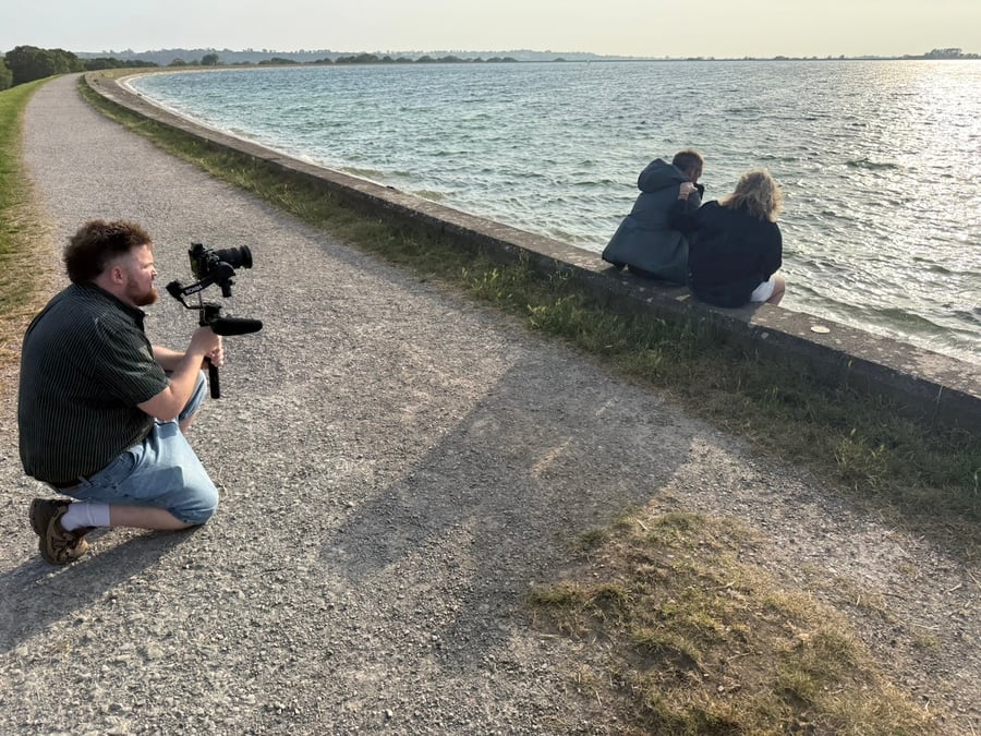 Camera man filming two people talking by the reservoir