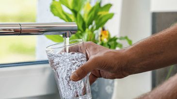 a hand filling up a glass of water from the tap