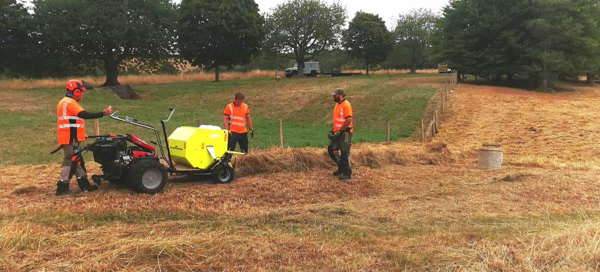 workmen in field baling hay