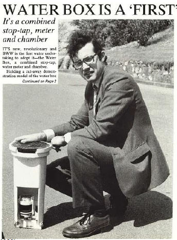 A black and white newspaper cutting of a bristol water employee with a water box. The headline reads 'water box is a first - it's a combined stop-tap, meter and chamber'. A man is on one knee in a suit next to the innovation. 