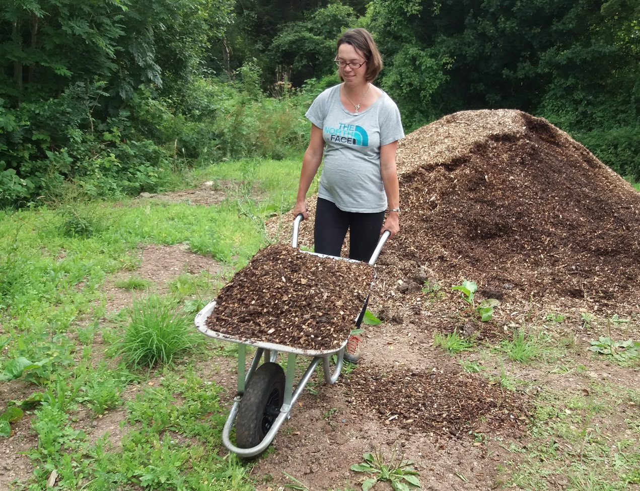 a woman wheeling a wheelbarrow full of soil