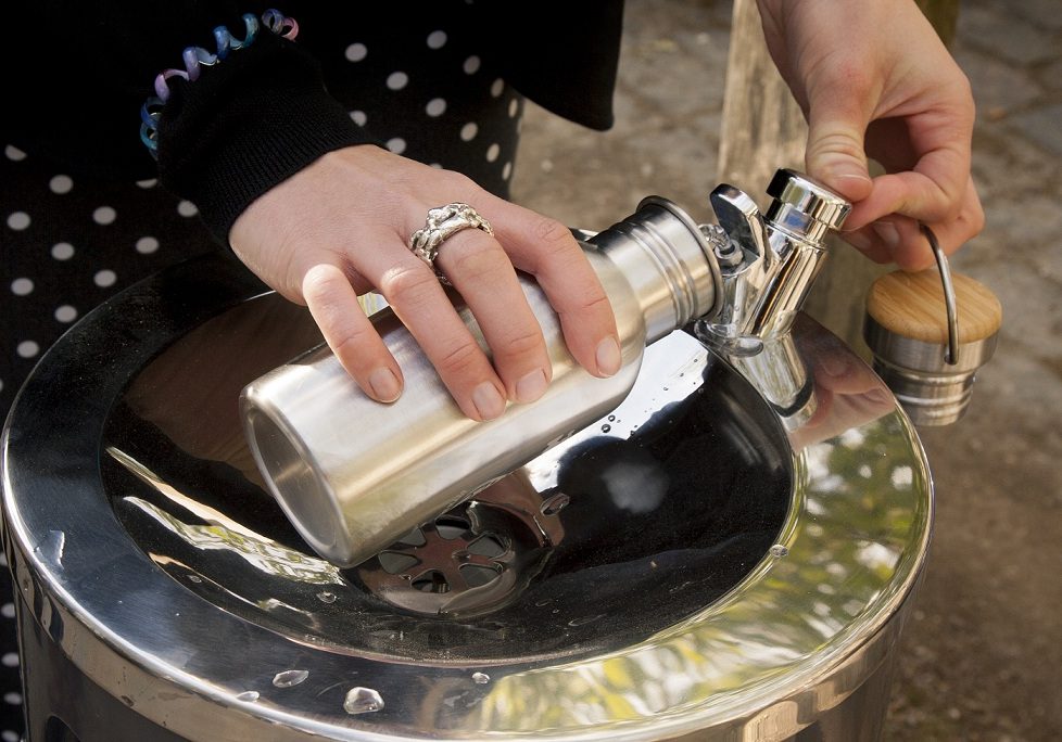 A person filling a metal water bottle from a water fountain A person filling a metal water bottle from a water fountain